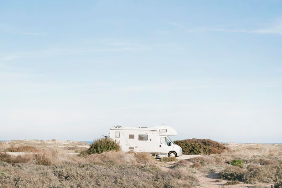 Person with dog sitting near RV campsite at sunset